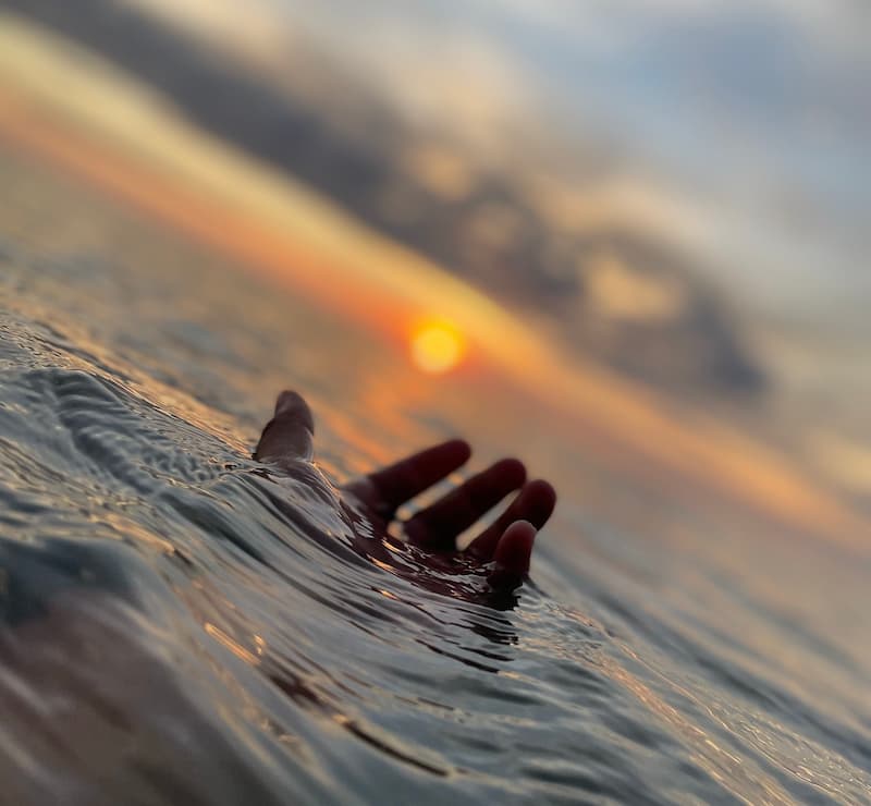 Image of a hand above the ocean's water symbolic of feeling trapped and weighed down by life