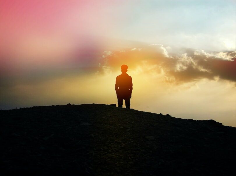 Image of a lonely man standing on a hill top trying to learn how to deal with loneliness