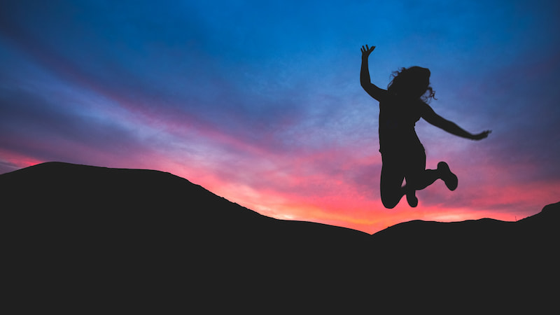 Image of a woman jumping up in joy having fun alone